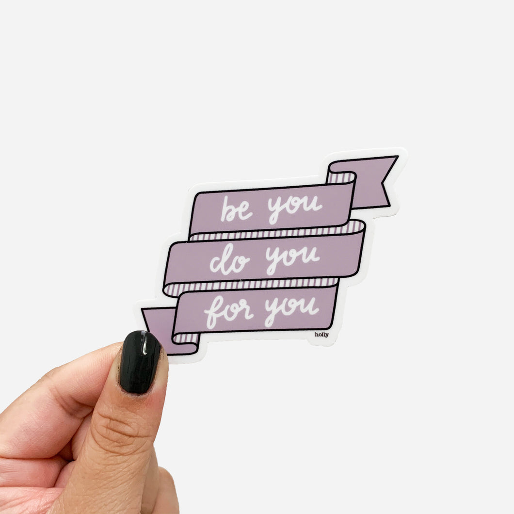 A sticker featuring a purple banner and text that reads, Be you do you for you.