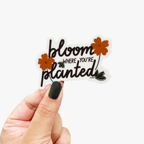 A sticker featuring flowers and leaves around text that reads, Bloom where you’re planted.