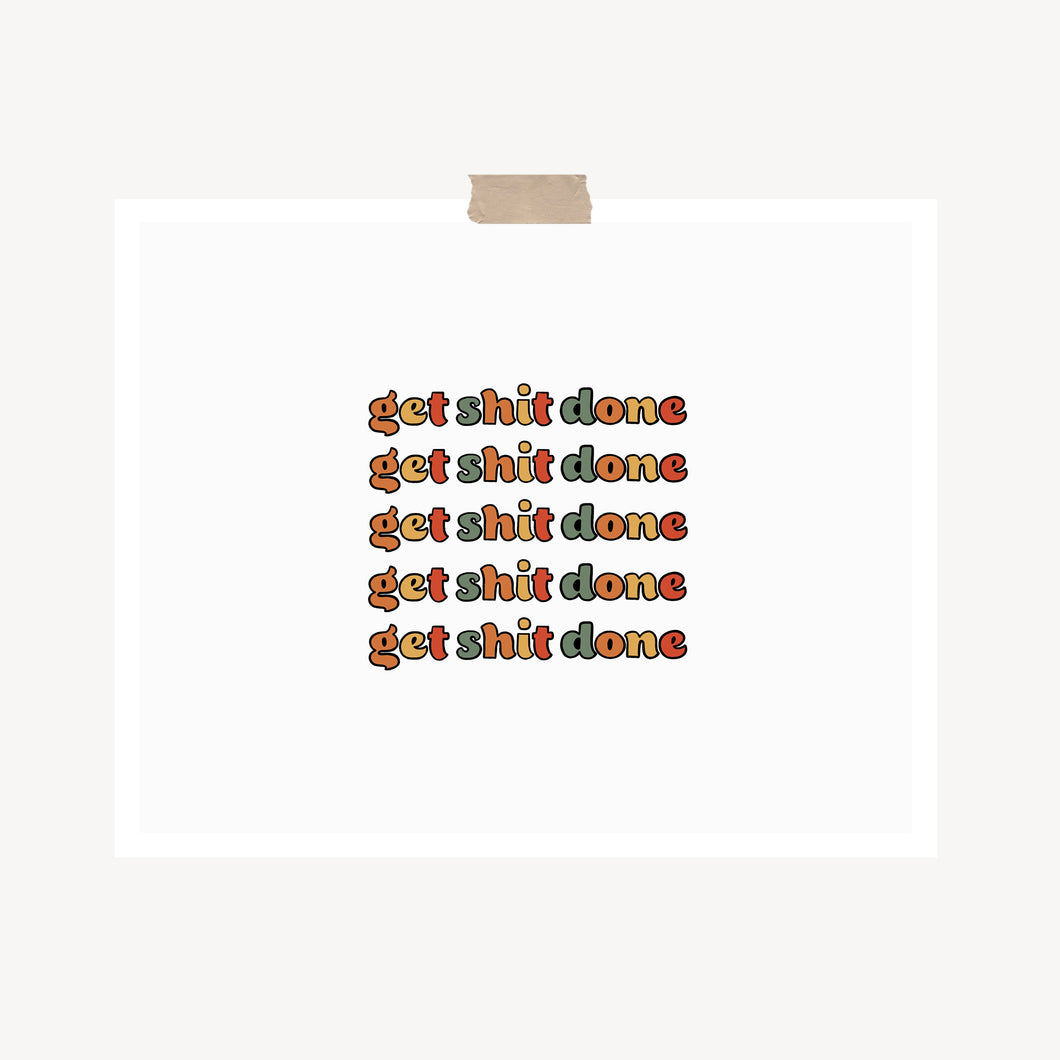 An art print featuring the text, “Get shit done,” written in retro bubble text and muted colors hung with a piece of kraft tape on the top.