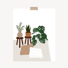 Load image into Gallery viewer, An art print featuring a monstera, snake plant, and eucalyptus plant on wooden stools and a rug next to two floor pillows hung with a piece of kraft tape on the top.
