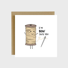 Load image into Gallery viewer, A funny greeting card featuring a sewing thread spool with a loose string in the shape of a heart that is threaded through a needle and text that reads, I’m sew into you.
