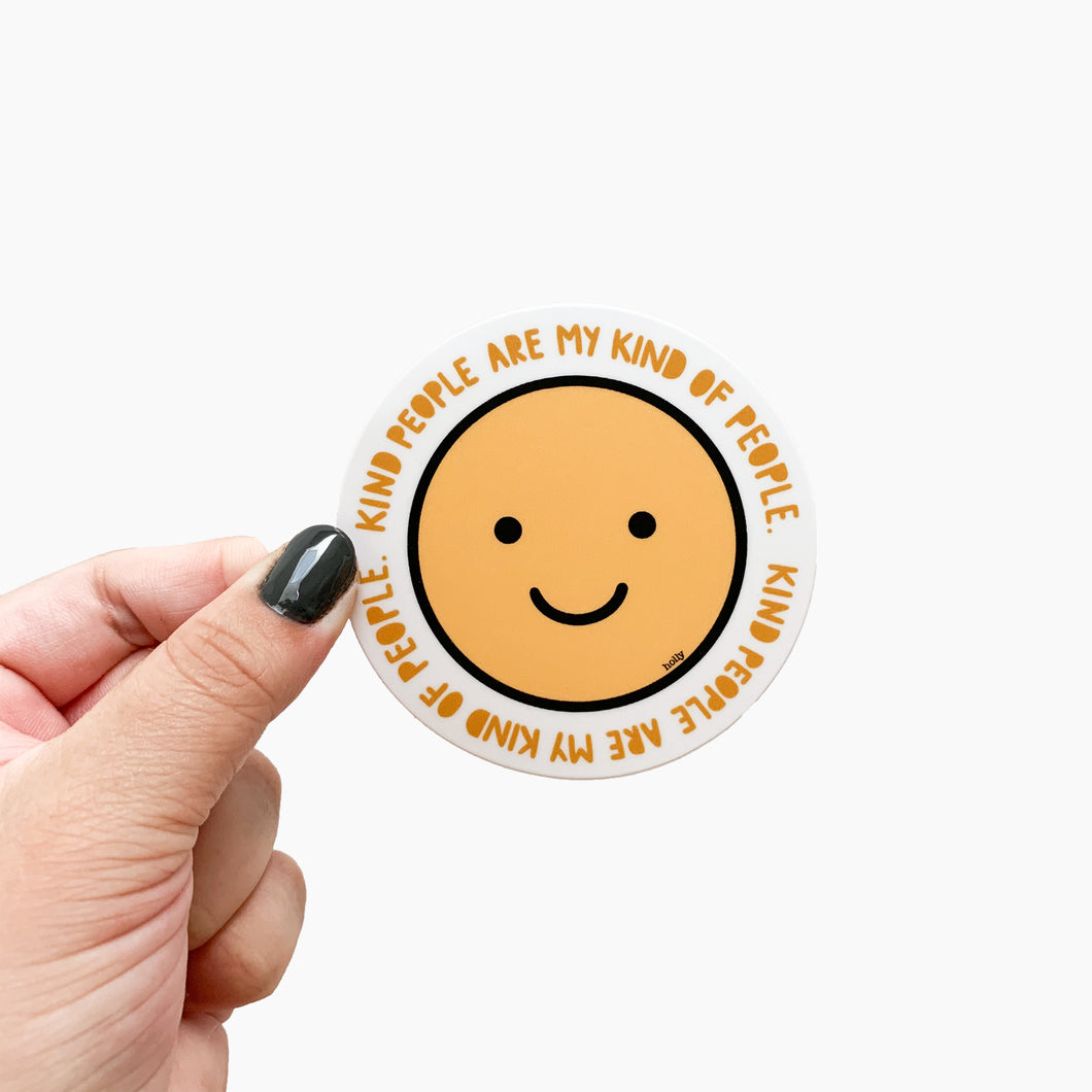 A circle sticker featuring a yellow happy face and text in a circle around it that reads, Kind people are my kind of people.