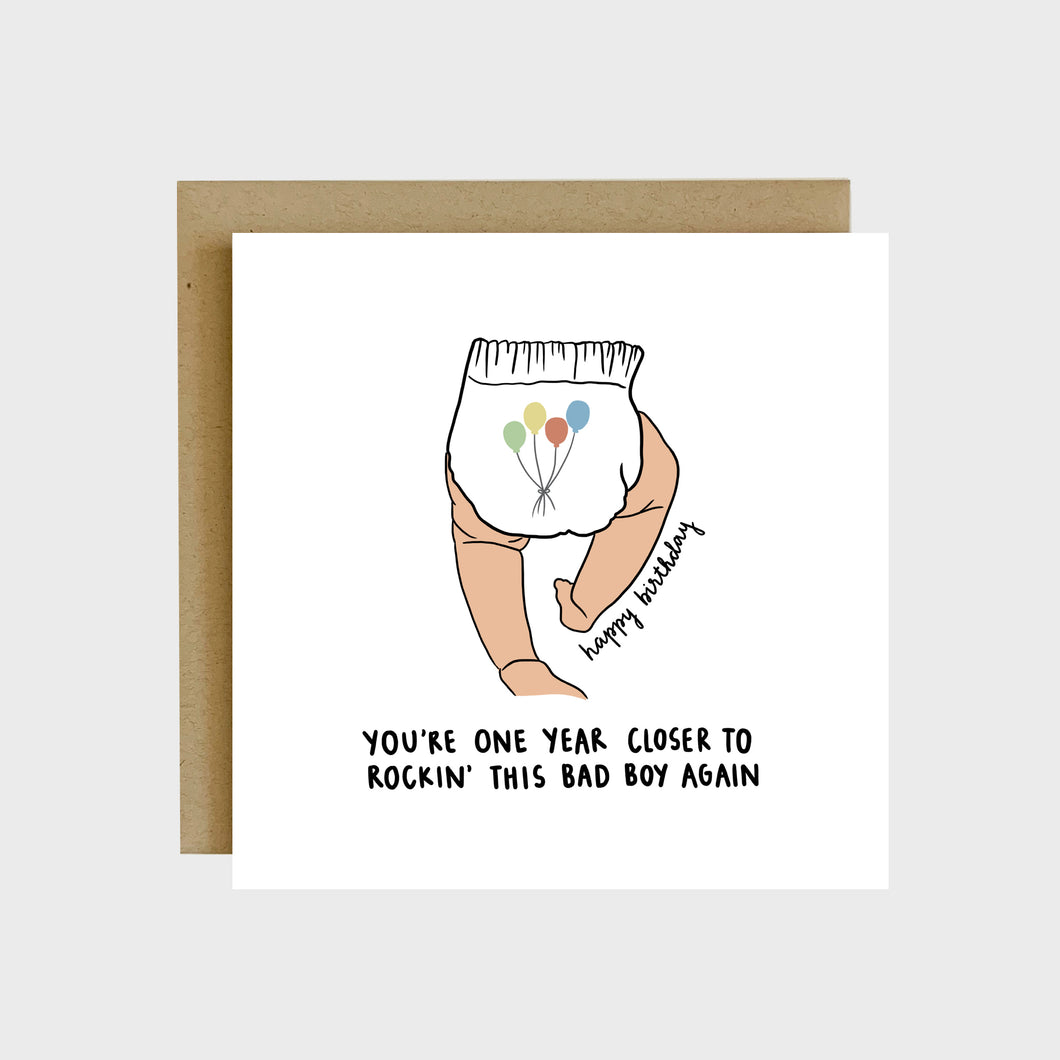 A funny greeting card featuring the back of a baby’s legs and a diaper with colorful balloons on it and text that reads, Happy Birthday, you’re one year closer to rockin’ this bad boy again.